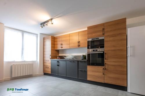 une cuisine avec des armoires en bois et un four à plaques de cuisson dans l'établissement BNB TOULOUSE - Le Gaston douillet - Clim - WiFi - Plein centre, à Tournefeuille