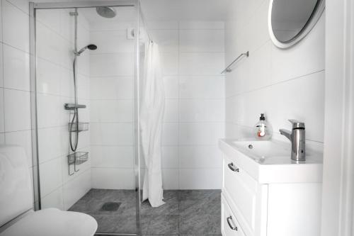 a white bathroom with a shower and a sink at Skärgårdslägenhet med havsutsikt i Sankt Anna! NR1 in Sankt Anna