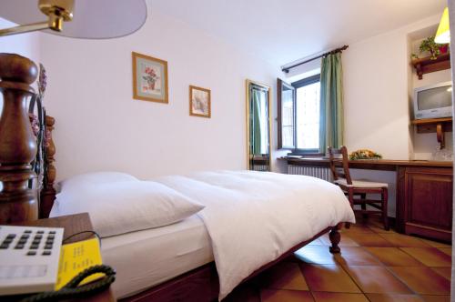a bedroom with a bed and a desk and a window at Albergo Ristorante della Posta in Morcote