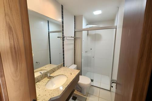 a bathroom with a sink and a toilet and a mirror at Apartamentos em Rio Quente com maravilhosa área de lazer e excelente localização in Rio Quente