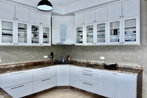 a white kitchen with white cabinets and a sink at Bens White House in AÃ¯n el Ksob
