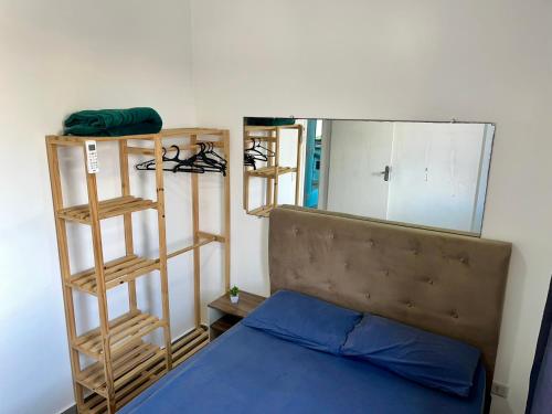 a small bedroom with a bed and a mirror at Apartamento pé na areia praia Tombo in Guarujá