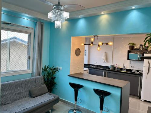 a kitchen with blue walls and a bar with stools at Apartamento pé na areia praia Tombo in Guarujá
