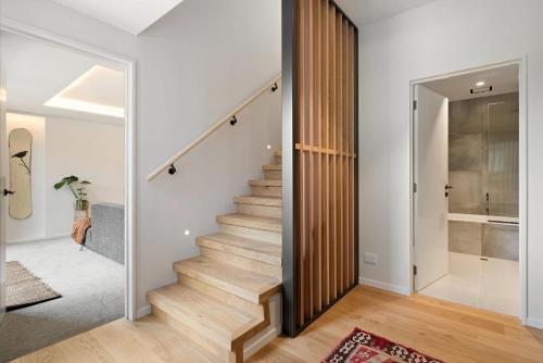 - un escalier dans une maison dotée de murs blancs et de parquet dans l'établissement Stunning Mountain Views in Queenstown-Hot tub, à Queenstown