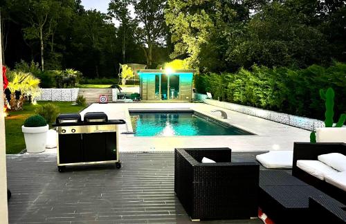 - une piscine dans une cour avec des chaises et une table dans l'établissement Villa avec piscine 35 min de Paris, à Étiolles