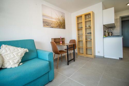 a living room with a blue couch and a table at Zeebries Studio in Ostend