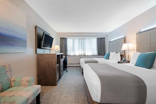 a hotel room with two beds and a flat screen tv at Best Western Plus Sands in Vancouver