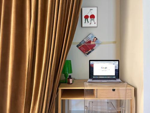 a desk with a laptop computer on a table with a curtain at Nest Blevio apartment with private garage in Blevio