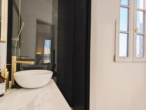 - une salle de bains avec un bol blanc sur un comptoir dans l'établissement Appart coquet avec vue - Alesia, à Paris