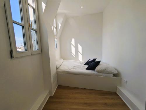 un petit lit dans une chambre avec une fenêtre dans l'établissement Appart coquet avec vue - Alesia, à Paris
