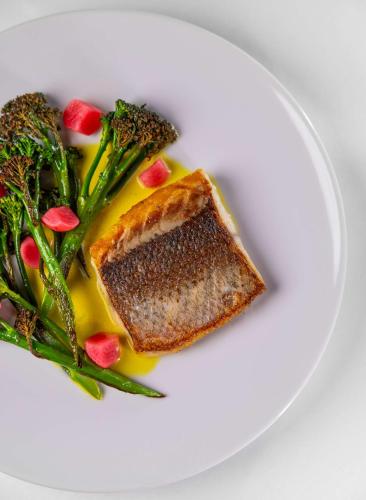a white plate with a piece of fish and vegetables at Radisson Blu Hotel, Lucerne in Luzern