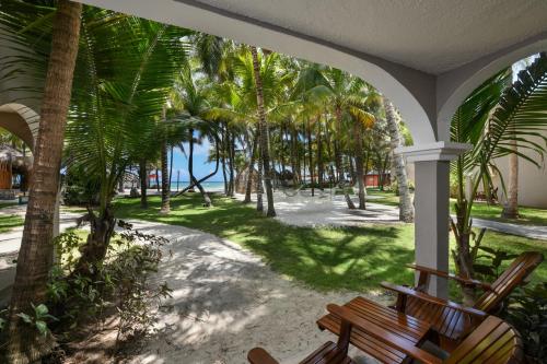 a porch with a bench and palm trees at El Dorado Seaside Palms, Catamarán, Ecoturistic Ranch, All & More Inclusive - Adults Only in Akumal