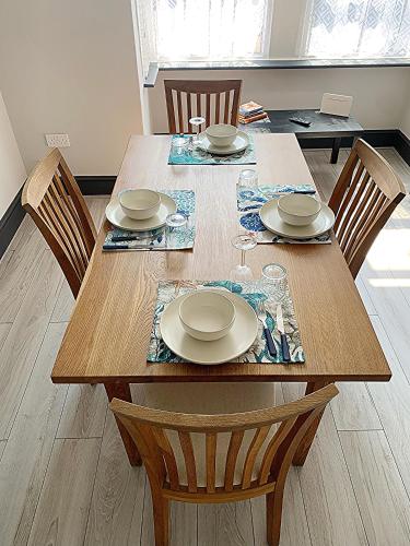 a wooden table with chairs and plates on it at Dreamstay Apartments London Garden Central Tube Olympic in London