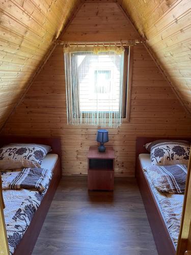a attic room with two beds and a window at Domki letniskowe ROSSA in Jarosławiec