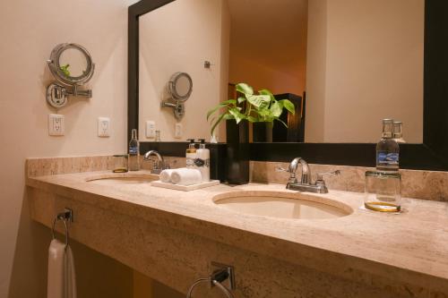 a bathroom with two sinks and a large mirror at Hidden Beach Resort Au Naturel Adults Only, All & More Inclusive in Akumal
