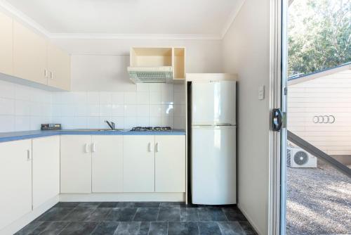 a kitchen with white cabinets and a refrigerator at Echo Holiday Parks - Windsor Gardens in Adelaide