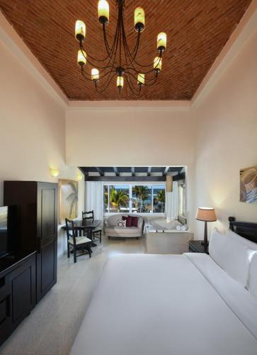 a bedroom with a large bed and a living room at Hidden Beach Resort Au Naturel Adults Only, All & More Inclusive in Akumal