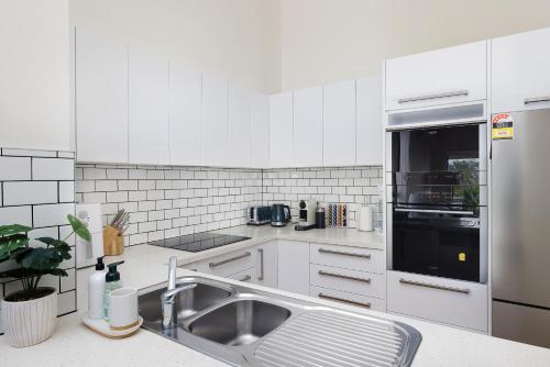 a white kitchen with a sink and a refrigerator at Fore Dek 4 in Soldiers Point