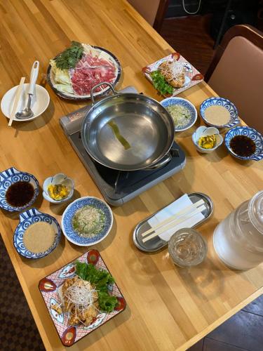 a table with plates of food and a pan on it at Madarao Lainstons in Iiyama