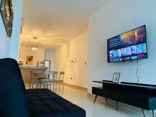a living room with a couch and a tv on the wall at Departamento 2Hab con Patio & Parrillera - A 10min del Consulado Americano in Guayaquil