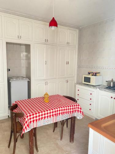 a kitchen with a table with a red and white table cloth at Le bien être in Kelibia