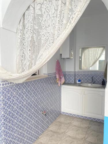 a kitchen with a sink and a window with a curtain at Le bien être in Kelibia