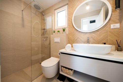 ein Badezimmer mit Waschbecken, Toilette und Spiegel in der Unterkunft Seaside house for families with children Cove Ramascica, Trogir - 23368 in Marina