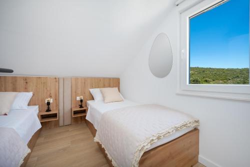 ein weißes Schlafzimmer mit zwei Betten und einem Fenster in der Unterkunft Seaside house for families with children Cove Ramascica, Trogir - 23368 in Marina