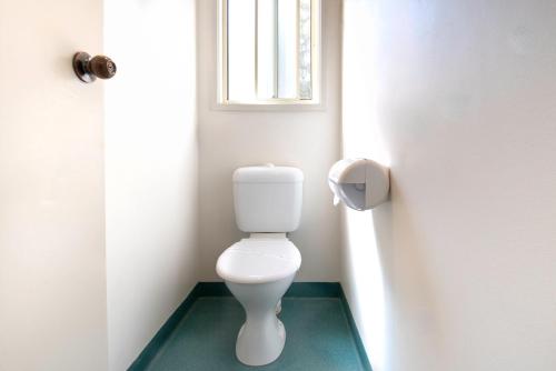 a white toilet in a bathroom with a window at Echo Holiday Parks - Windsor Gardens in Adelaide