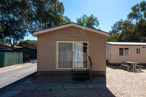 a small building with a door and a picnic table at Echo Holiday Parks - Windsor Gardens in Adelaide