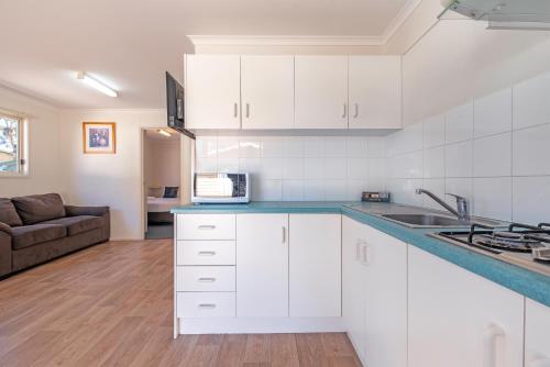 a kitchen with white cabinets and a living room at Echo Holiday Parks - Windsor Gardens in Adelaide