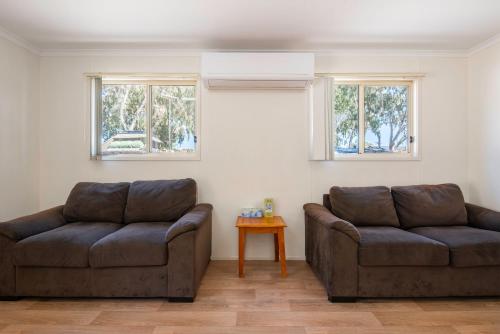 two brown couches in a living room with windows at Echo Holiday Parks - Windsor Gardens in Adelaide