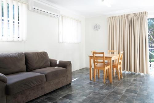 a living room with a couch and a table and chairs at Echo Holiday Parks - Windsor Gardens in Adelaide