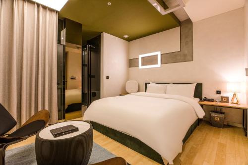 a bedroom with a large white bed and a desk at Hotel The Designers Cheongnyangni in Seoul