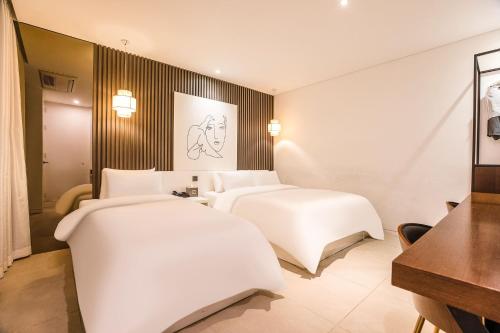 two beds in a hotel room with white sheets at Hotel The Designers Cheongnyangni in Seoul