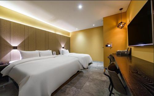 a hotel room with two beds and a flat screen tv at Hotel The Designers Cheongnyangni in Seoul