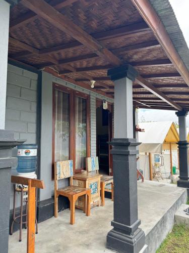 a patio with a wooden pergola with chairs and a table at Black Lava Hostel and Lodge in Kintamani