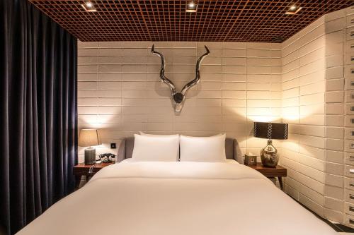 a bedroom with a large white bed with antlers on the wall at Hotel The Designers Cheongnyangni in Seoul