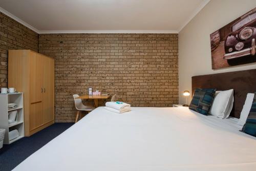 a bedroom with a large bed and a brick wall at Echo Holiday Parks - Windsor Gardens in Adelaide