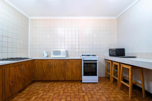 a kitchen with wooden cabinets and a stove at Echo Holiday Parks - Windsor Gardens in Adelaide