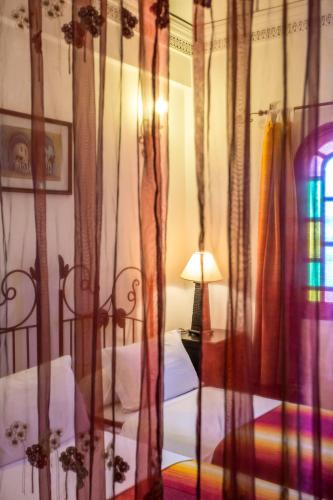 a bedroom with a bed and a lamp and curtains at Riad Jnane Mogador in Marrakech