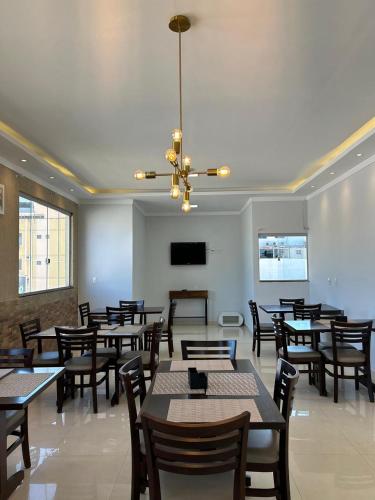 a dining room with tables and chairs and a chandelier at Hotel Nova Jerusalém in Goiânia