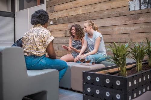 a group of three women sitting on a wall at De Draecke Hostel in Ghent