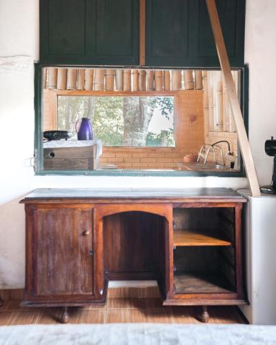 a kitchen with a wooden desk and a window at Chalé Angico - Refúgio Namata in Pirenópolis