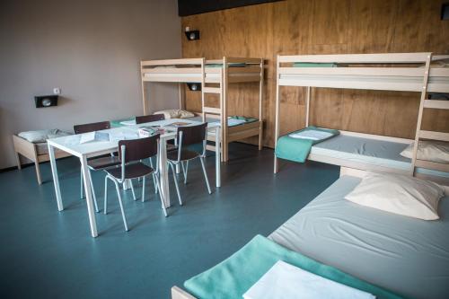 a room with three bunk beds and a table and chairs at De Draecke Hostel in Ghent