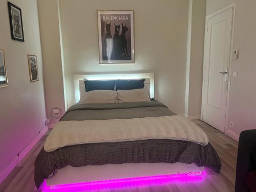 - une chambre avec un lit orné d'une lumière rose dans l'établissement Appartement gare Nice ville, à Nice