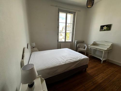 une chambre avec un lit, un bureau et une fenêtre dans l'établissement Charmant T2 en centre-ville, 1er étage, La Roche-Posay, pour 4 pers, animaux bienvenus - FR-1-541-107, à La Roche-Posay