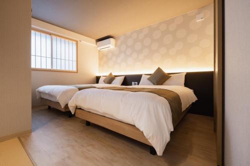 two beds in a bedroom with a window at BEPPU -Nagomi- in Beppu