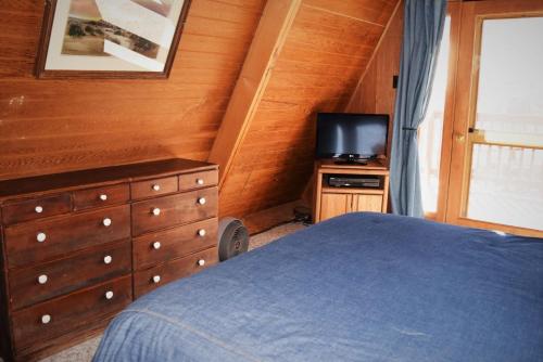 a bedroom with a bed and a dresser with a television at Claim Jumper A-Frame 1 - On The River - Pet Friendly - WiFi - Cable - Wood Burning Fireplace in Red River