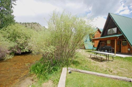a cabin with a picnic table next to a river at Claim Jumper A-Frame 2 - On The River - WiFi - Cable - Wood Burning Fireplace in Red River